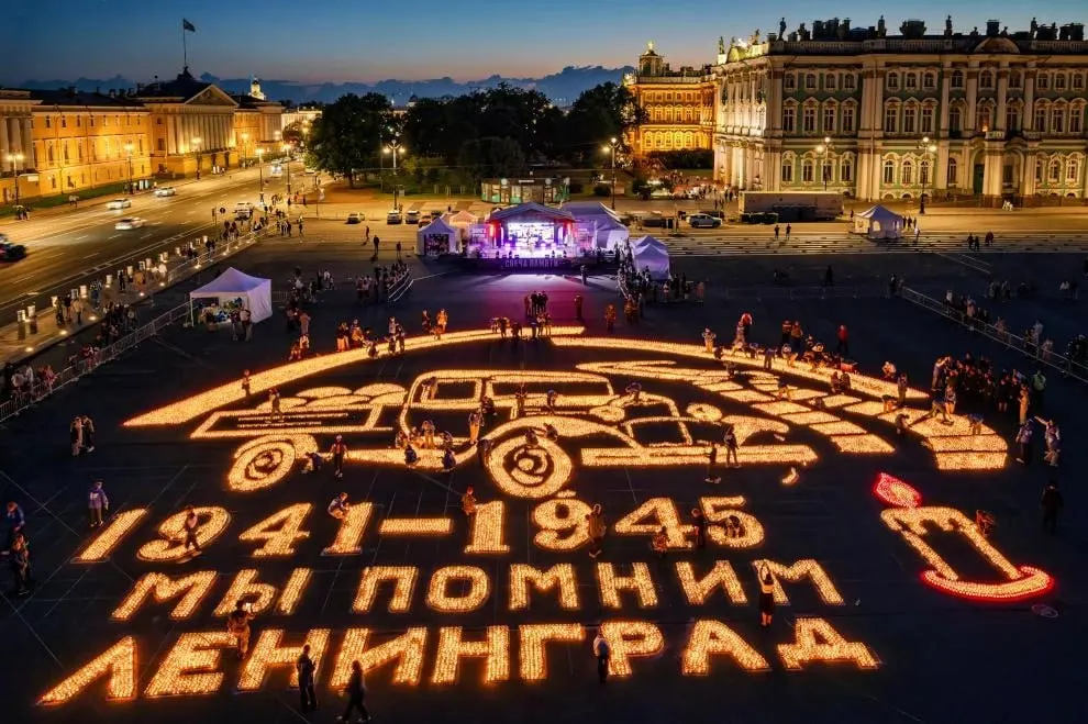 Ночью на Дворцовой площади прошла акция «Свеча памяти» в честь 85‑й годовщины начала Великой Отечественной войны: участники выложили из свечей композицию с разорванным кольцом блокады и грузовиком ГАЗ‑АА.