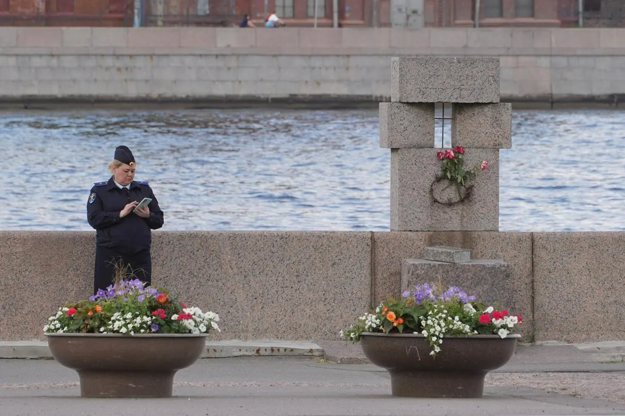 Возле памятника жертв политических репрессий на Воскресенской набережной появились цветы; у мемориала дежурит полиция, рядом лежат мешки с мусором.