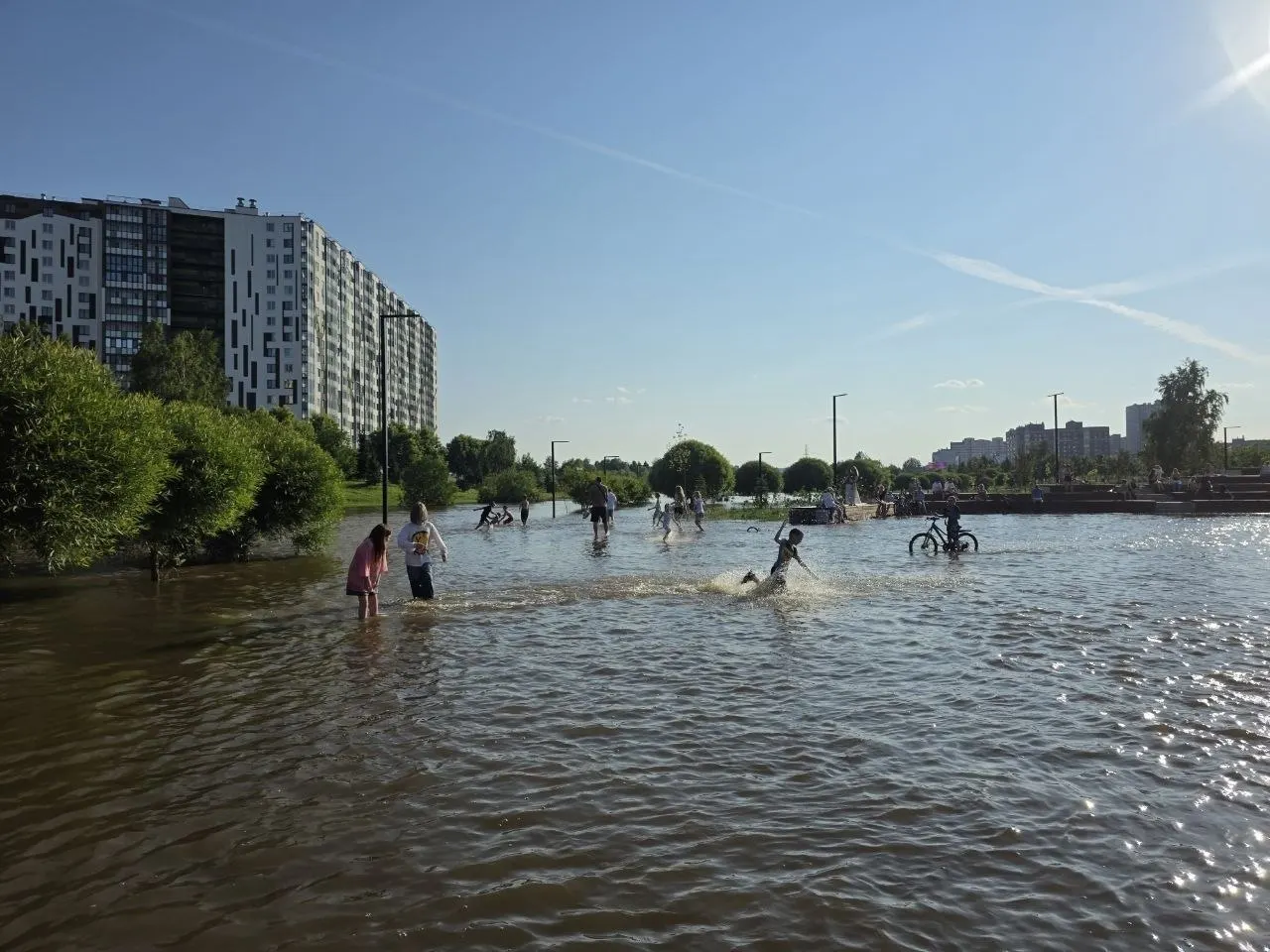 После сильных дождей часть парка Оккервиль в Кудрове оказалась под водой — жители выходили на сапбордах, дети плескались, а велосипедисты шли вброд.