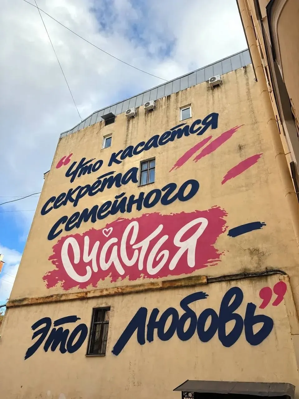 На стене здания в Басковом переулке, 12, появился мурал с фразой президента о секрете семейного счастья; автор — Филипп Дульмаченко.